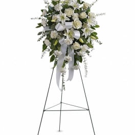 White floral standing spray on a metal easel with ribbon