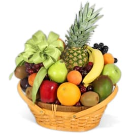 Wicker gift basket filled with assorted fresh fruits and topped with a green bow