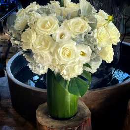 White roses and pale blooms arranged in a tall green vase