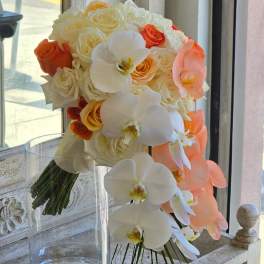 Bouquet of white and peach roses with white orchids in a clear glass vase