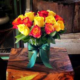Bouquet of yellow and red roses in a glass vase with a green ribbon