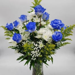 Blue roses and white daisies in a clear glass vase