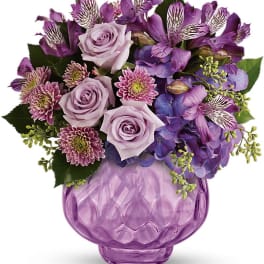 Purple bouquet of roses, alstroemeria, and hydrangea in a lavender vase