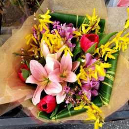 Bouquet of pink lilies, yellow orchids, and red tulips wrapped in paper