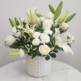 White lilies and roses arranged in a textured white vase