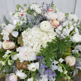 Large white floral arrangement with pale pink roses and purple accents
