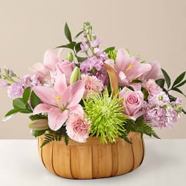 Pink lilies and roses arranged in a wooden basket