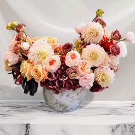 Bouquet of peach and cream flowers in a round vase