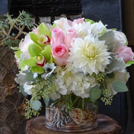 Pink roses and white flowers arranged in a glass vase
