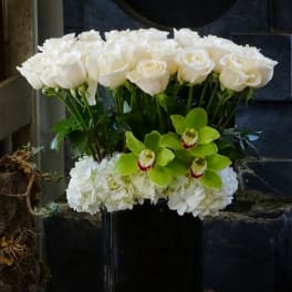 White roses and green orchids in a black vase
