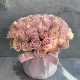 Pink roses arranged in a white ribbed vase with a pink ribbon