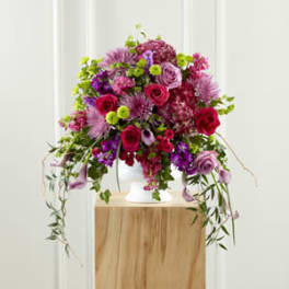 Large pink and purple floral arrangement in a white vase