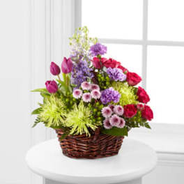 Mixed bouquet in a wicker basket with purple, pink, and green flowers