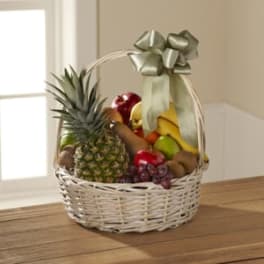 Fruit basket with pineapple, bananas, grapes, and other fruit in a wicker basket