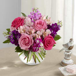 Pink and purple bouquet of roses and mixed blooms in a clear glass vase