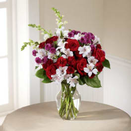 Bouquet of red roses and white flowers in a clear glass vase
