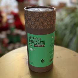Cylindrical cocoa mix container with a green label on a table