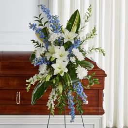 White lilies and blue flowers arranged over a casket
