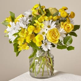 Yellow roses and white daisies in a clear glass vase