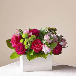 Pink roses and mixed blooms arranged in a white box