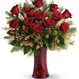 Red roses arranged in a tall red vase with greenery and gold accents