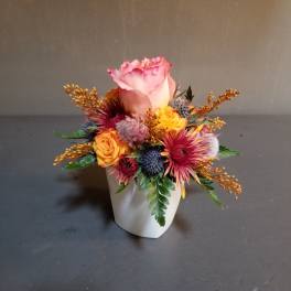 Pink rose arrangement in a white vase with yellow and red accent flowers