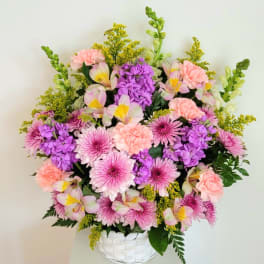 Pink and purple mixed flowers arranged in a white basket vase