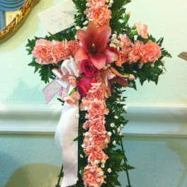 Cross-shaped floral funeral spray with pink carnations and lilies