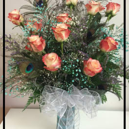 Tall bouquet of peach roses with peacock feathers in a vase