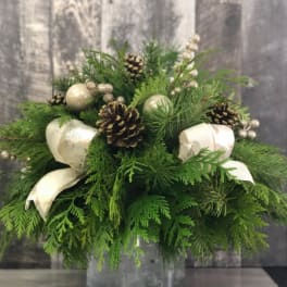 Evergreen arrangement with pinecones, cream ornaments, and ribbon in a glass vase
