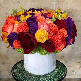 Bright mixed bouquet in a white vase with roses and ranunculus