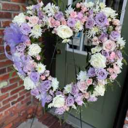 Heart-shaped floral wreath with lavender, pink, and white flowers on an easel