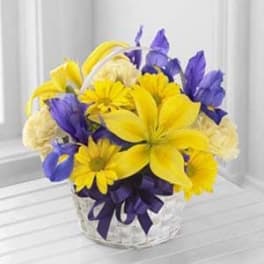 Yellow and purple flowers arranged in a clear glass vase