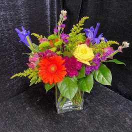 Colorful mixed bouquet in a clear glass vase with gerbera daisies and roses