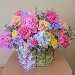 Mixed pink, peach, yellow, and lavender flowers in a woven basket
