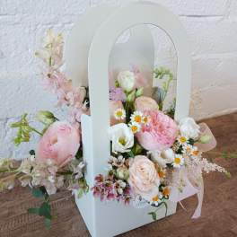Pastel flower arrangement in a white handled box with pink and white blooms