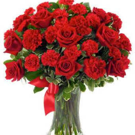 Red roses and carnations in a clear glass vase with a red ribbon