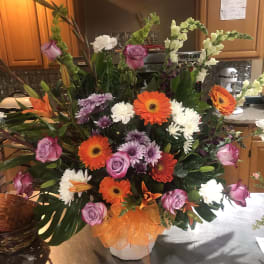 Large mixed bouquet in a white vase with orange ribbon