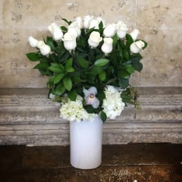 White roses and hydrangeas arranged in a tall white vase