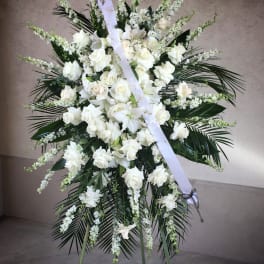 Large white funeral spray on a stand with ribbon