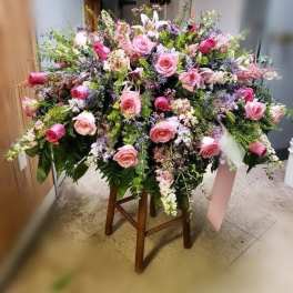 Large pink rose and lily floral arrangement on a wooden stand