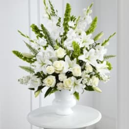 White floral arrangement in a white vase with tall green accents