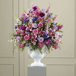 Large pink and purple mixed flower arrangement in a white vase