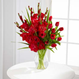 Red tulips and gladiolus in a clear glass vase