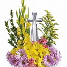 Pastel yellow and lavender floral arrangement with pink accents surrounding a crystal cross figurine