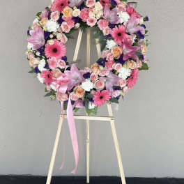 Pink and white floral wreath on a wooden easel with a ribbon