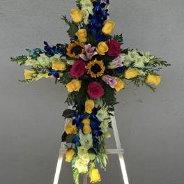 Cross-shaped floral tribute on an easel with roses and orchids