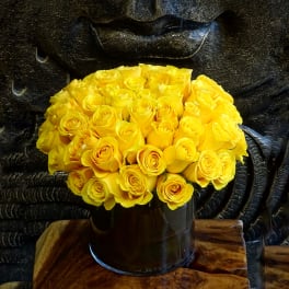Bouquet of yellow roses in a dark cylindrical vase