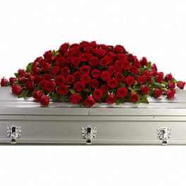 Large spray of red roses arranged across a silver casket