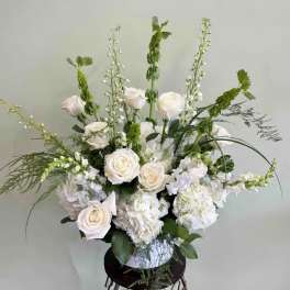White roses and hydrangeas in a vase with tall green accents